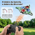 Avião de controle remoto verde em voo ao ar livre com controle nas mãos e duas baterias exibidas no painel.