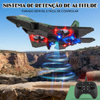 Avião de controle remoto verde em voo sobre paisagem rochosa com controle exibido no canto inferior.