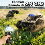 Carro de controle remoto preto e cinza em movimento sobre gramado com controle remoto em primeiro plano.