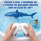Tubarão azul por controle remoto nadando em piscina enquanto duas mãos operam o controle branco.