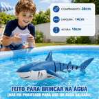 Tubarão azul por controle remoto na piscina diante de criança com controle e dimensões indicadas.